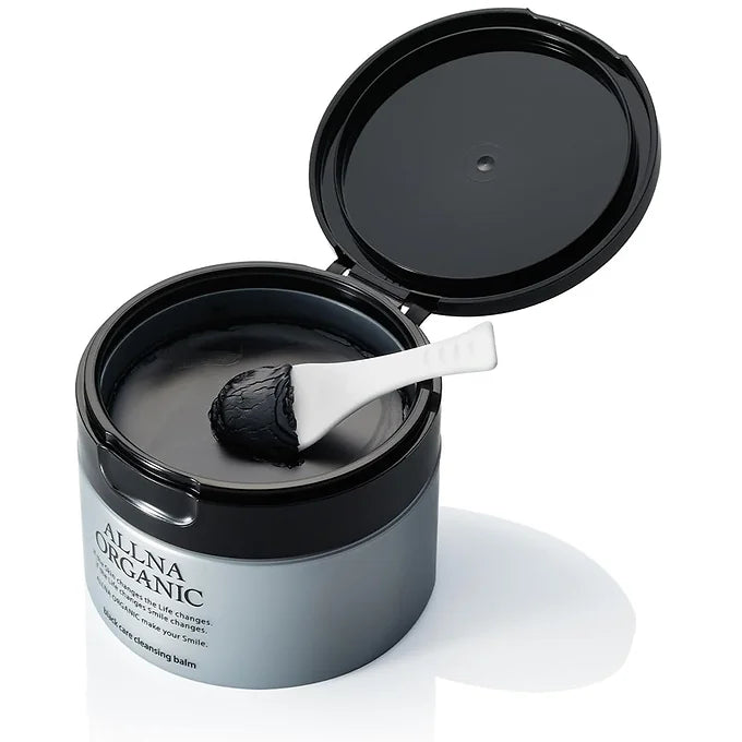 Black container of Allna Organic balm with a spoon inside on a white background
